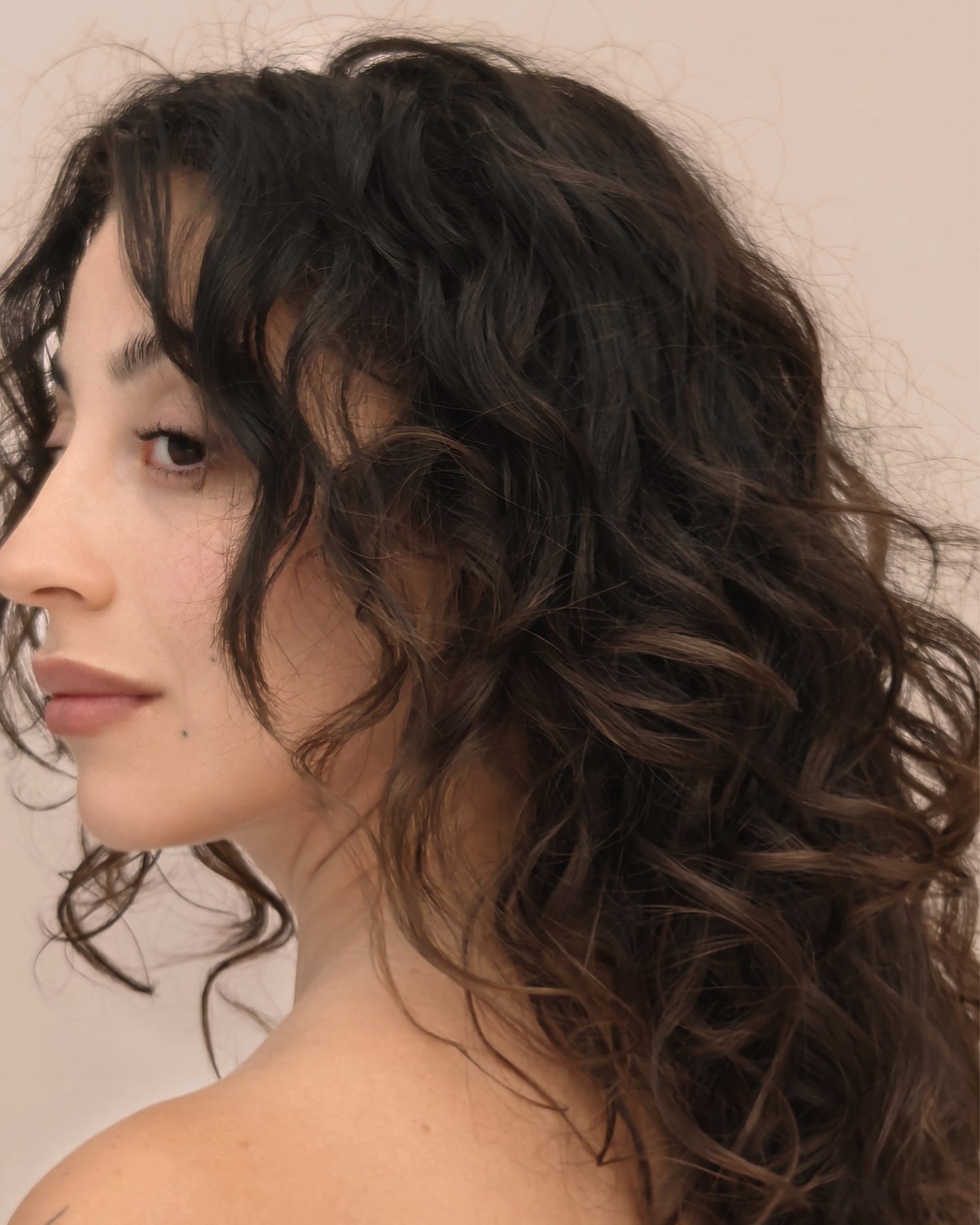 Chica morena de perfil con el cabello rizado.